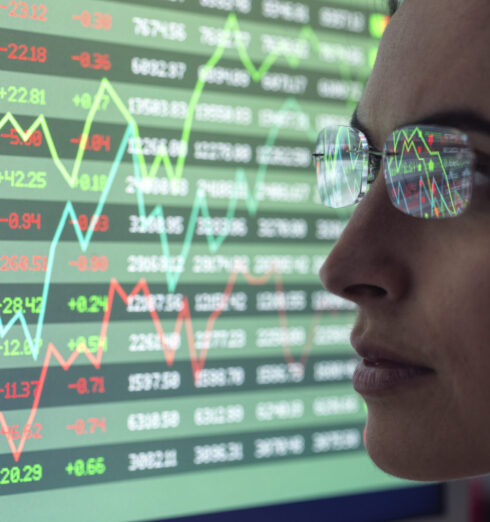 Female analyst viewing financial market data on a screen. Focused professional analyzing stock market data on screens