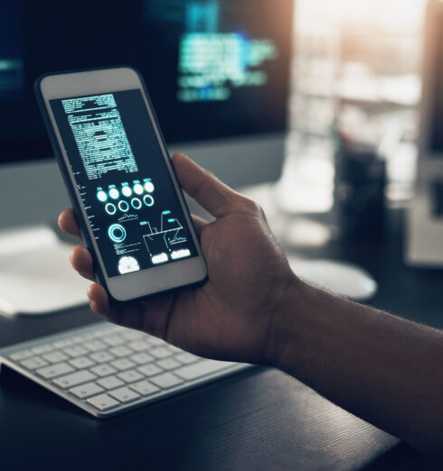 Cropped shot of an unrecognizable man using a cellphone in a modern office. Cropped shot of an unrecognizable man using a cellphone in a modern office.
