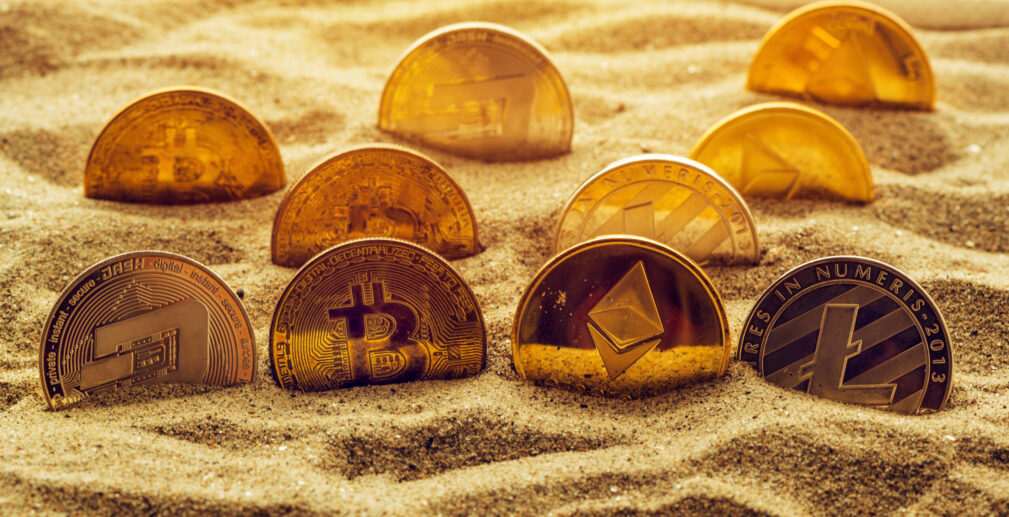 Cryptocurrency coins in sand Cryptocurrency coins in sand, conceptual image for lost and found valuables that are standing the test of time.